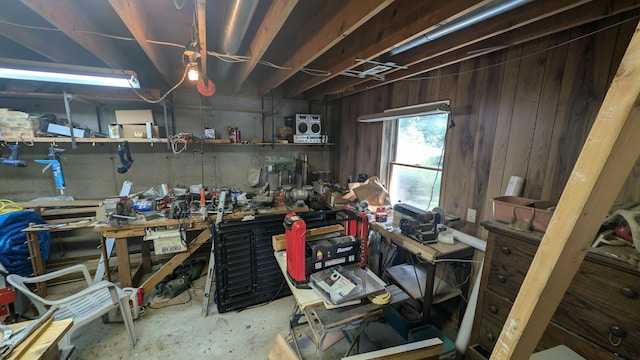 miscellaneous room featuring wooden walls, a workshop area, and concrete flooring