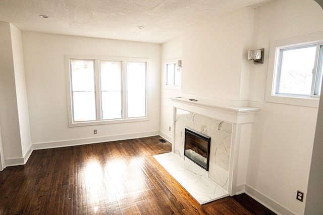 2552 N La Salle Gdns, Detroit, MI 48206 - unfurnished living room featuring baseboards, a textured ceiling, dark wood-style flooring, and a high end fireplace