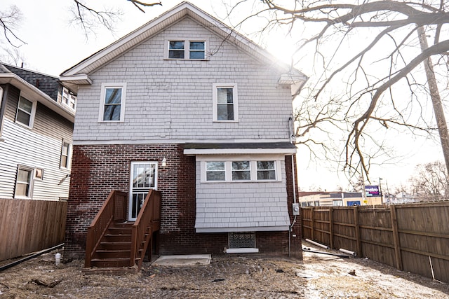 back of house with a fenced backyard and brick siding