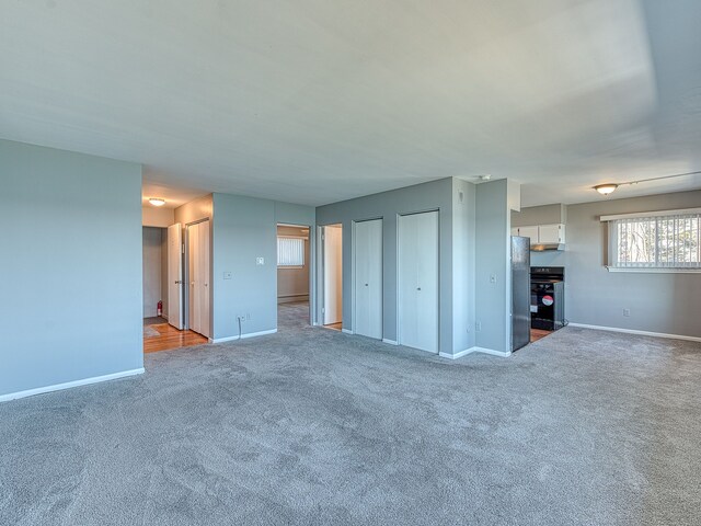 unfurnished living room with carpet and baseboards