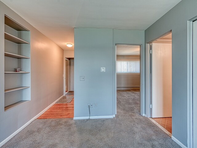 hall featuring baseboards and carpet flooring