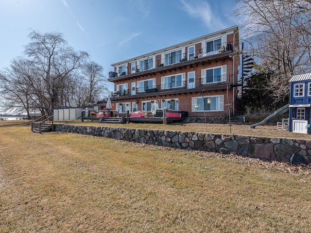 rear view of property with brick siding and a yard