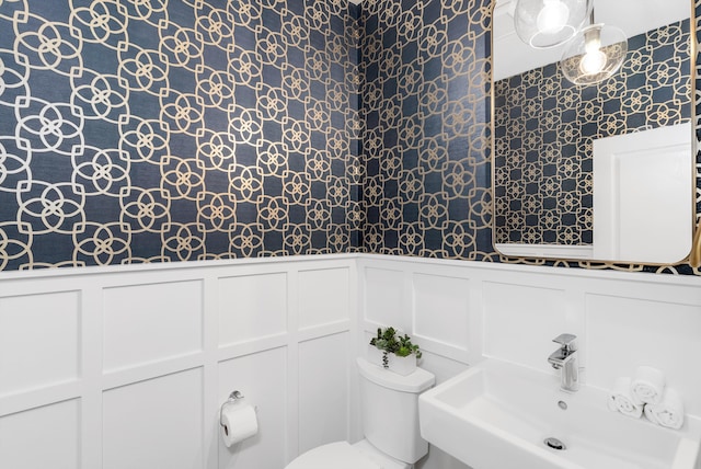 bathroom featuring a sink, toilet, and wainscoting