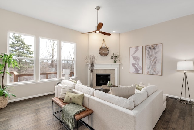 living area featuring a fireplace, a ceiling fan, dark wood-type flooring, and baseboards