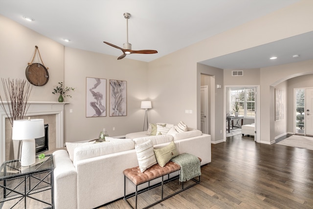 living area with wood finished floors, visible vents, baseboards, a fireplace, and arched walkways