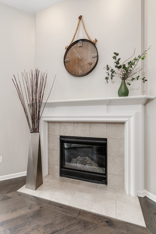 interior details with a tile fireplace, baseboards, and wood finished floors