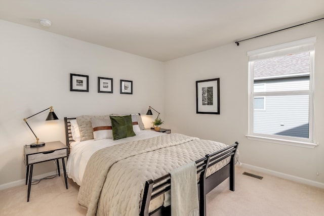 bedroom featuring visible vents, light carpet, and baseboards