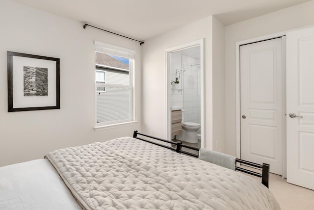 bedroom featuring connected bathroom and light colored carpet