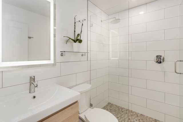 full bath with toilet, a stall shower, backsplash, tile walls, and vanity