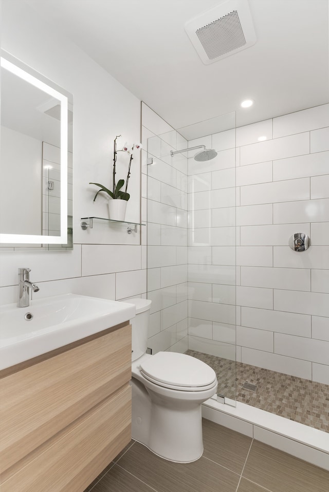 full bath with vanity, toilet, visible vents, and tiled shower