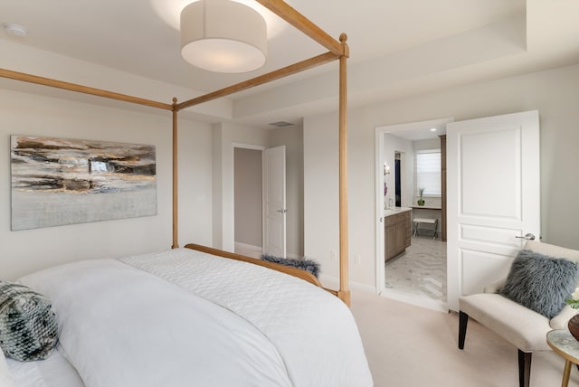 bedroom with light carpet, visible vents, ensuite bath, and baseboards