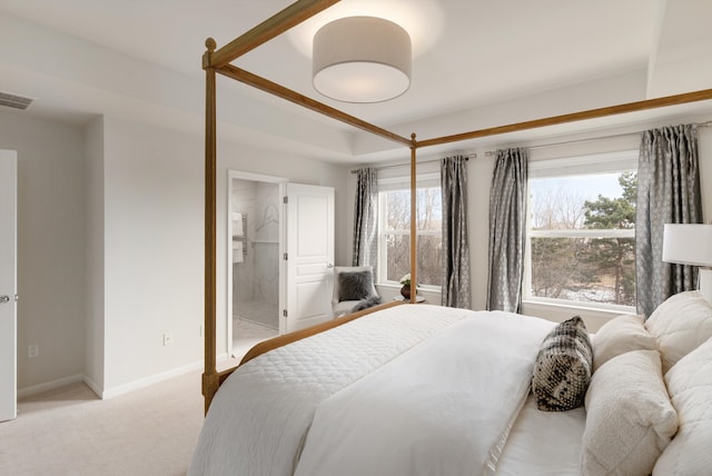 bedroom with light colored carpet, visible vents, ensuite bathroom, and baseboards