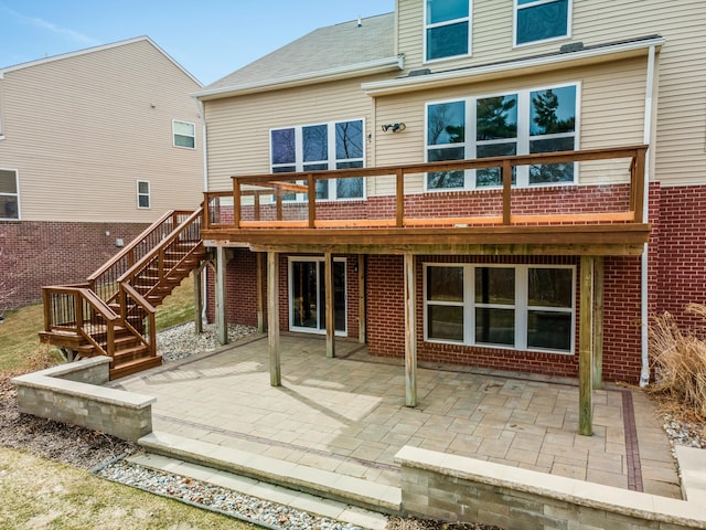 rear view of property with brick siding, stairway, a patio, and a deck