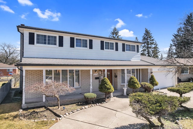 traditional-style house featuring fence, an attached garage, brick siding, and covered porch