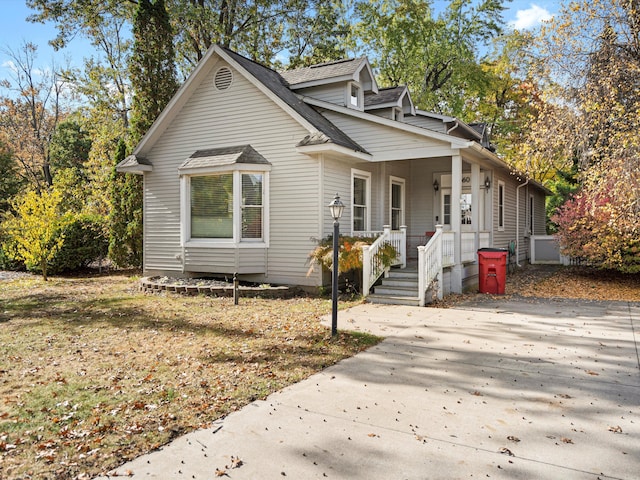 bungalow featuring covered porch and roof with shingles