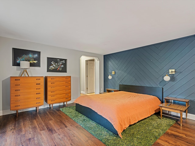 bedroom with an accent wall, baseboards, and wood finished floors