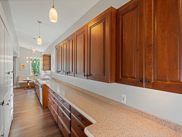 kitchen featuring dark wood-type flooring, a sink, decorative light fixtures, light countertops, and vaulted ceiling