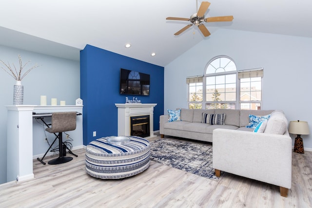 living area with a glass covered fireplace, recessed lighting, baseboards, and wood finished floors