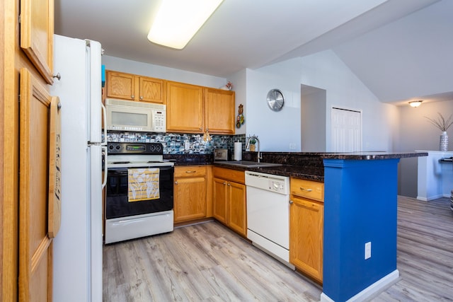 kitchen featuring tasteful backsplash, a peninsula, light wood-style floors, white appliances, and a sink