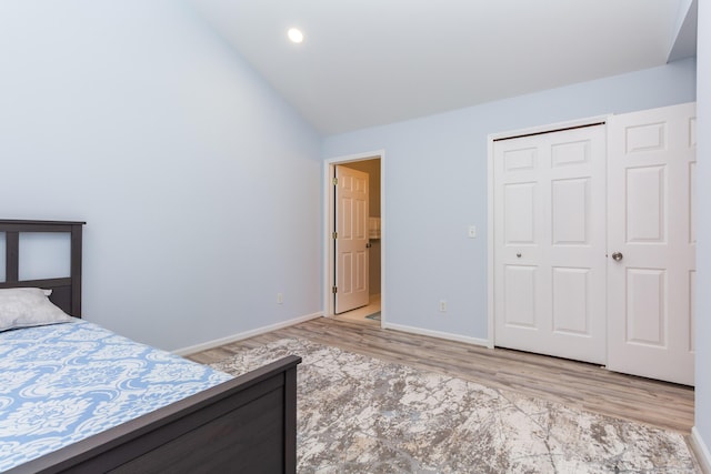 unfurnished bedroom featuring baseboards, vaulted ceiling, recessed lighting, wood finished floors, and a closet