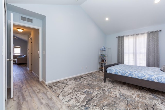 bedroom with lofted ceiling, wood finished floors, visible vents, and baseboards