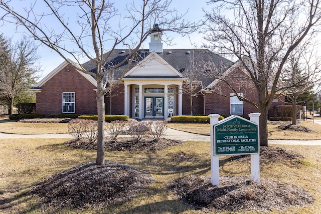 view of front of home with french doors, brick siding, and a chimney