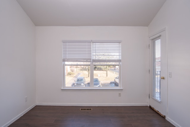 unfurnished room featuring visible vents, baseboards, and dark wood-style flooring