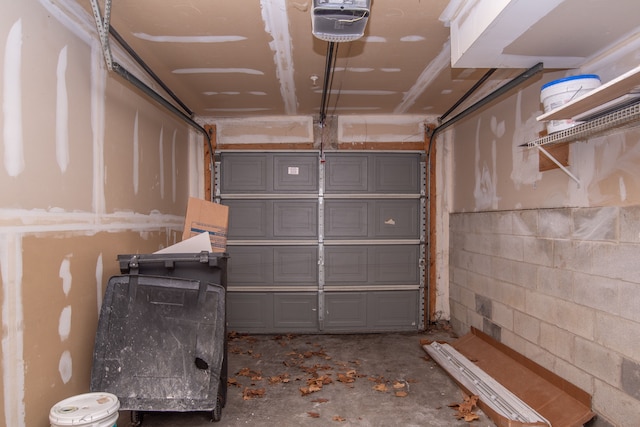 garage with a garage door opener and concrete block wall