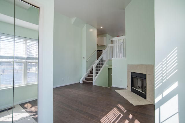 unfurnished living room with visible vents, baseboards, stairway, a fireplace, and wood finished floors