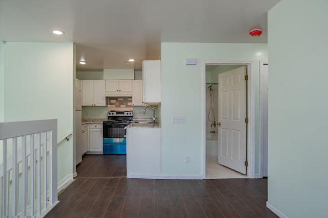 kitchen with tasteful backsplash, stainless steel electric stove, white cabinets, and dark wood-style flooring