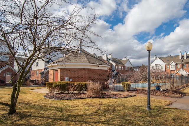 view of front of home with brick siding, a front lawn, fence, and a residential view