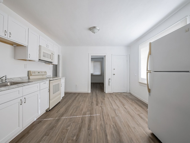 kitchen with white cabinets, white appliances, light wood-type flooring, and a sink