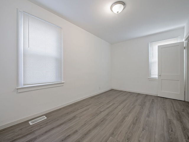 empty room with visible vents, baseboards, and wood finished floors