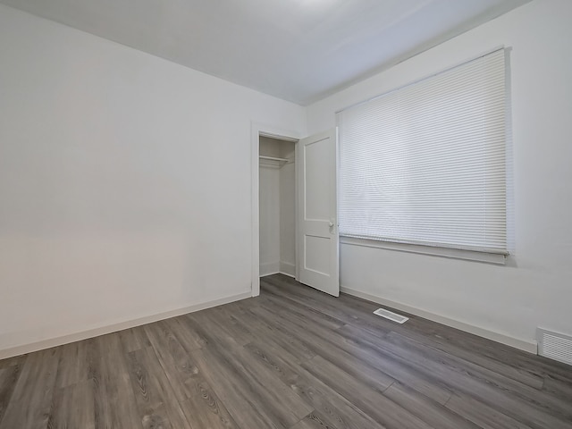 unfurnished bedroom with visible vents, baseboards, a closet, and wood finished floors