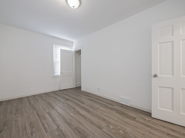 spare room featuring wood finished floors, visible vents, and baseboards