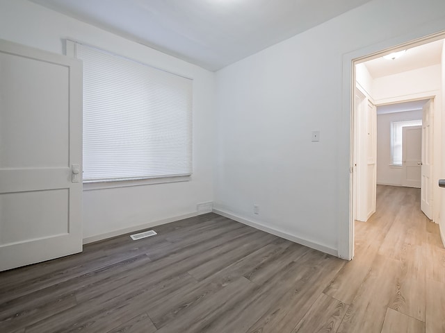 unfurnished room with wood finished floors, visible vents, and baseboards