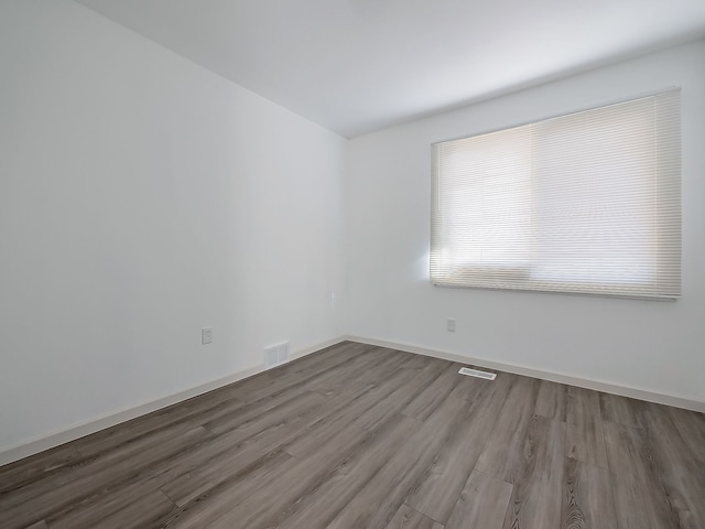 spare room with visible vents, baseboards, and wood finished floors