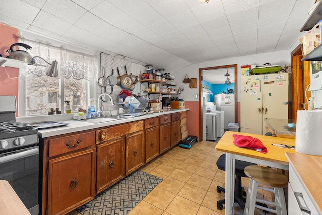 kitchen featuring a sink, a healthy amount of sunlight, light countertops, stainless steel gas range, and open shelves