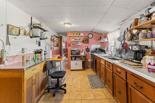 kitchen featuring open shelves, range with gas cooktop, light tile patterned flooring, and black microwave