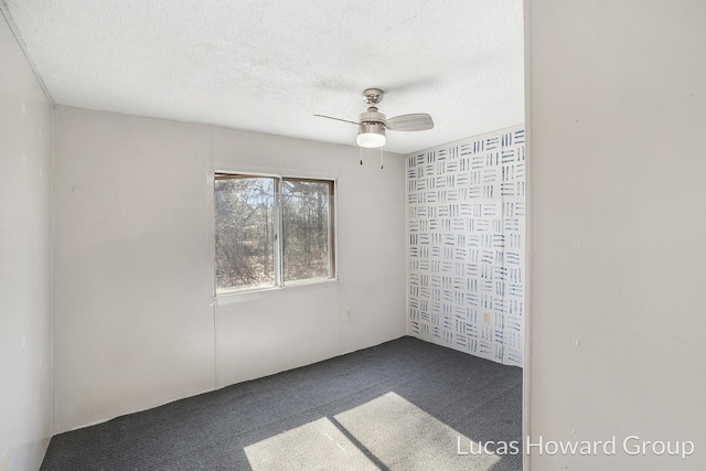 empty room with a textured ceiling, a ceiling fan, and dark colored carpet