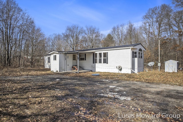 manufactured / mobile home with entry steps, an outbuilding, and a shed