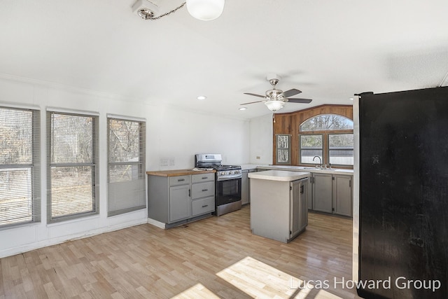 kitchen featuring light wood finished floors, gray cabinets, light countertops, vaulted ceiling, and appliances with stainless steel finishes