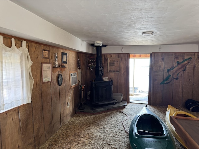 living area with carpet flooring, wood walls, and a wood stove