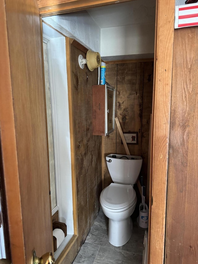 bathroom with toilet and wooden walls