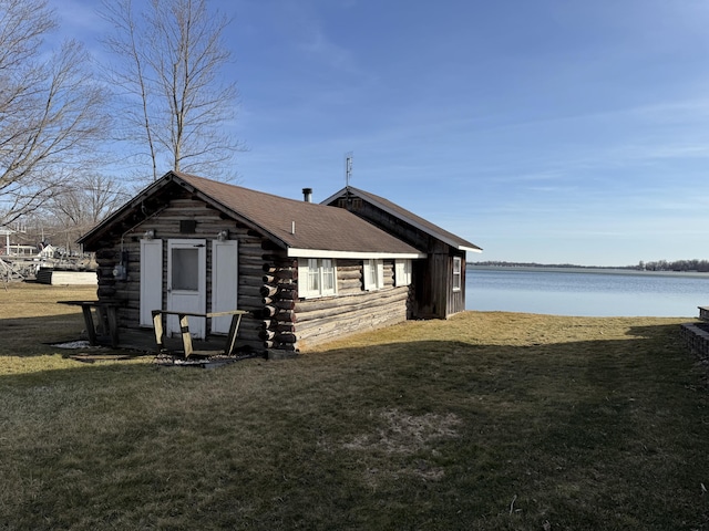 view of home's exterior with log exterior, a lawn, a water view, and a shingled roof