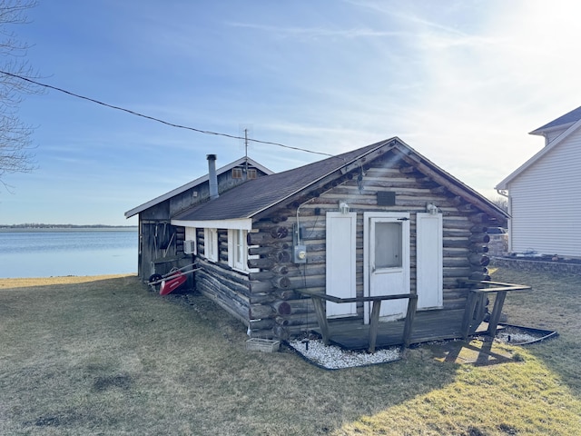 exterior space with log siding, a yard, and a water view