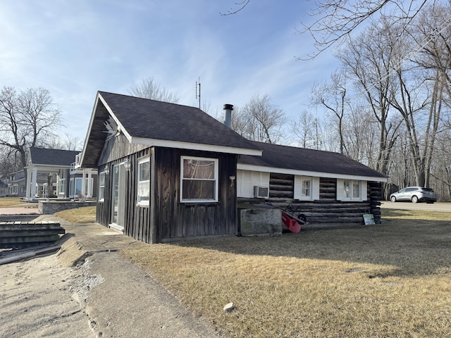 exterior space featuring a shingled roof and a front yard