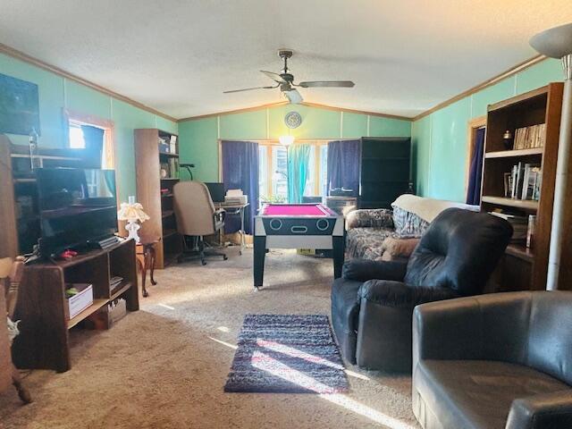 living area with lofted ceiling, a healthy amount of sunlight, carpet, and ornamental molding