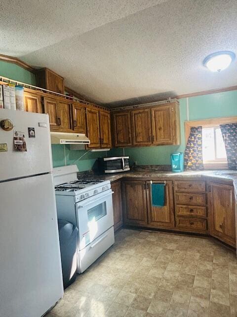 kitchen featuring under cabinet range hood, light floors, vaulted ceiling, brown cabinets, and white appliances