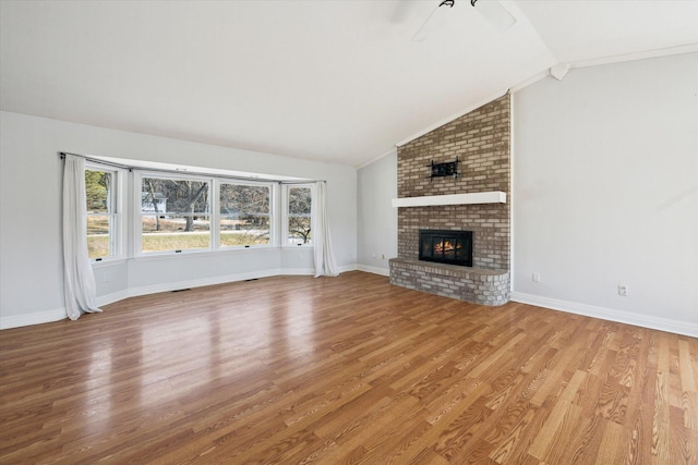 unfurnished living room with light wood finished floors, a brick fireplace, baseboards, and vaulted ceiling